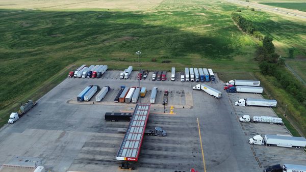 An aerial view of a truck terminal with tractors and trailers parked across a paved yard