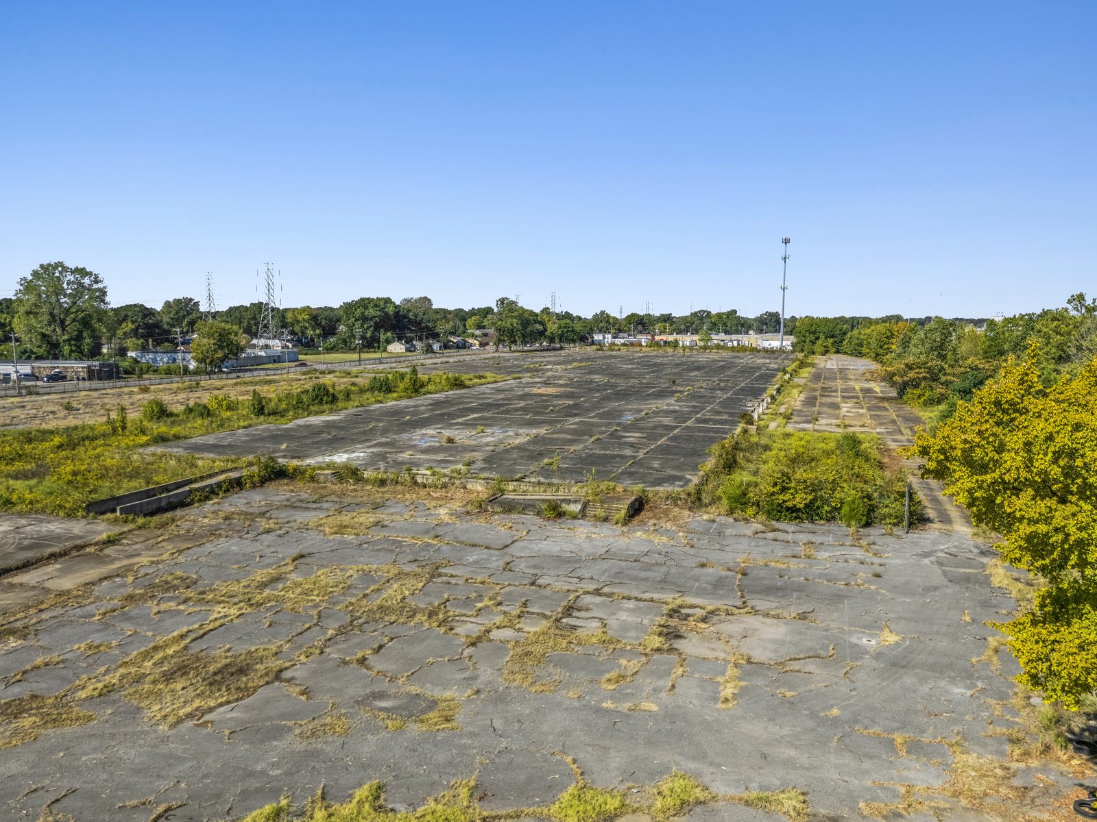 Aerial from one end of the site looking down the length of the concrete pad, with trees along the right side.