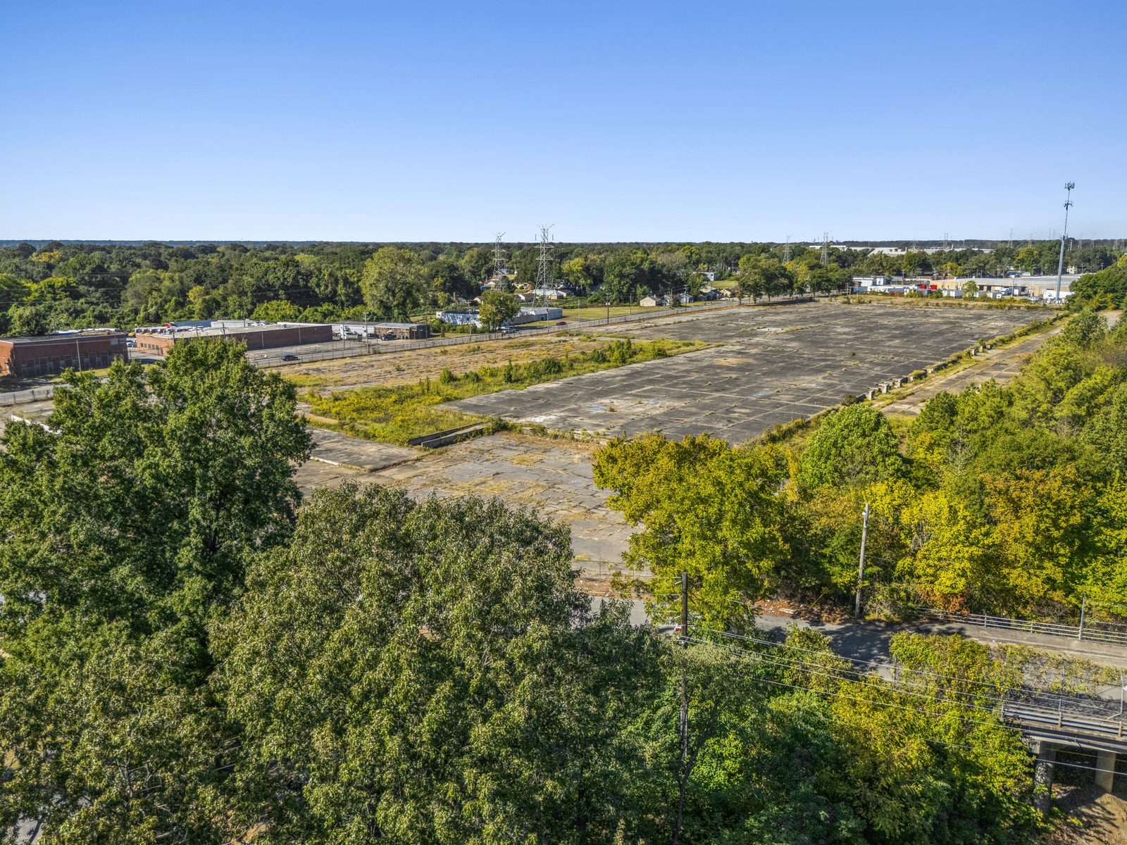 Aerial looking across trees to the concrete pad, with brick buildings beyond it.