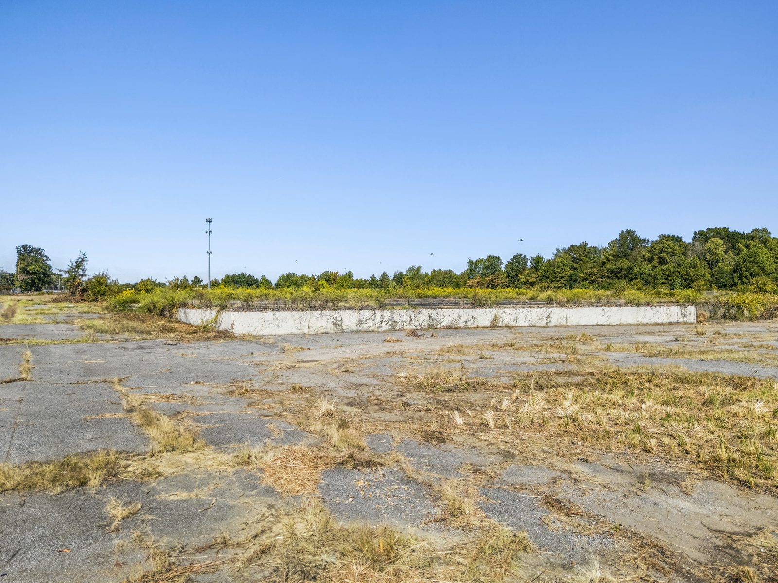 Ground view across the concrete slab toward a long, low concrete wall.