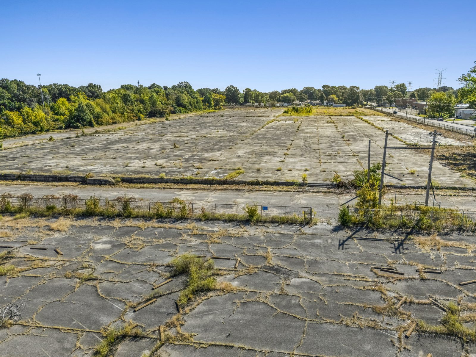 Low aerial over cracked concrete in the foreground and the main concrete slab beyond a low fence.