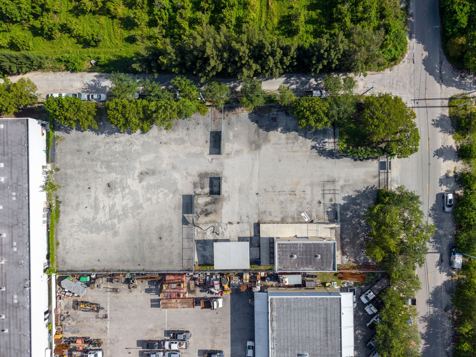 Straight down drone view of the rectangular paved yard, with the warehouse and canopy along one edge and the street beside the site.