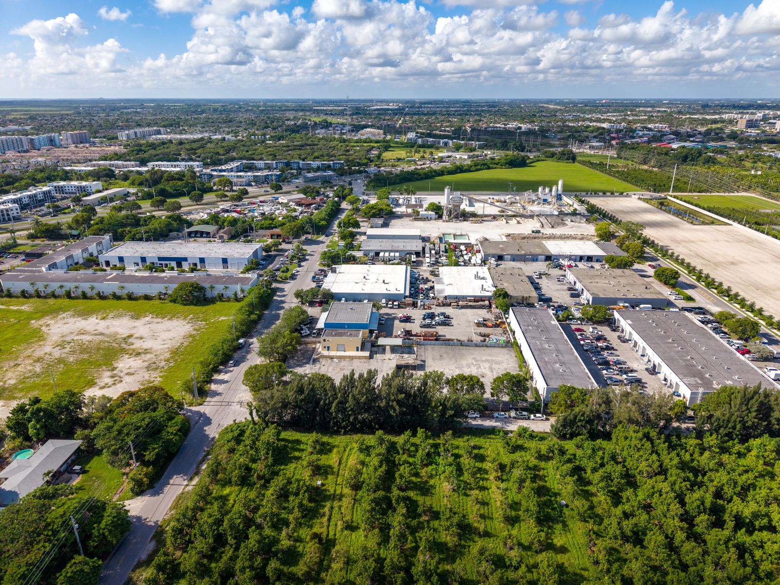 Wide aerial overview from above the site looking across the surrounding industrial park and open land.