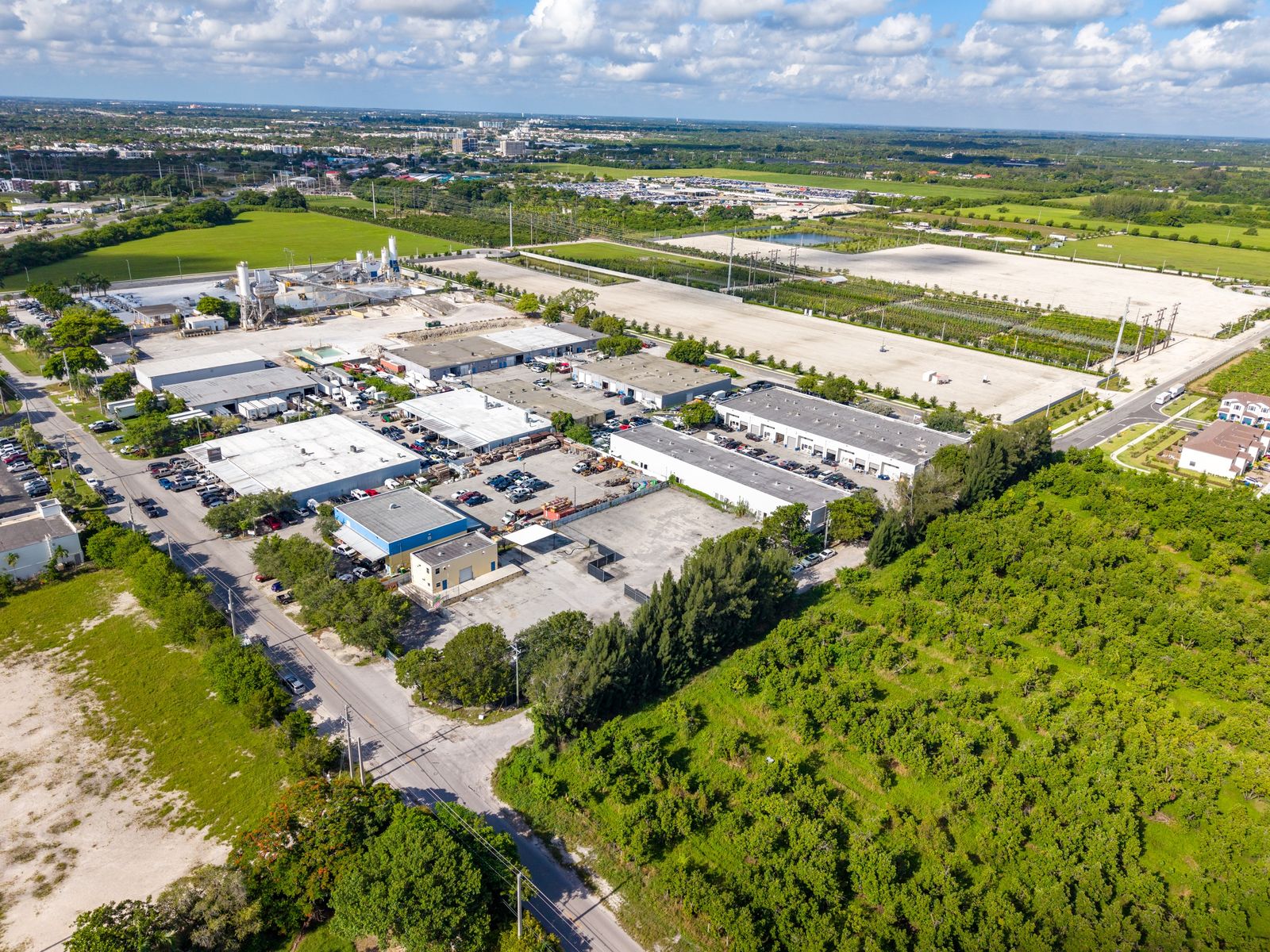 Aerial view from above the site looking across nearby fields and rows of warehouse buildings.