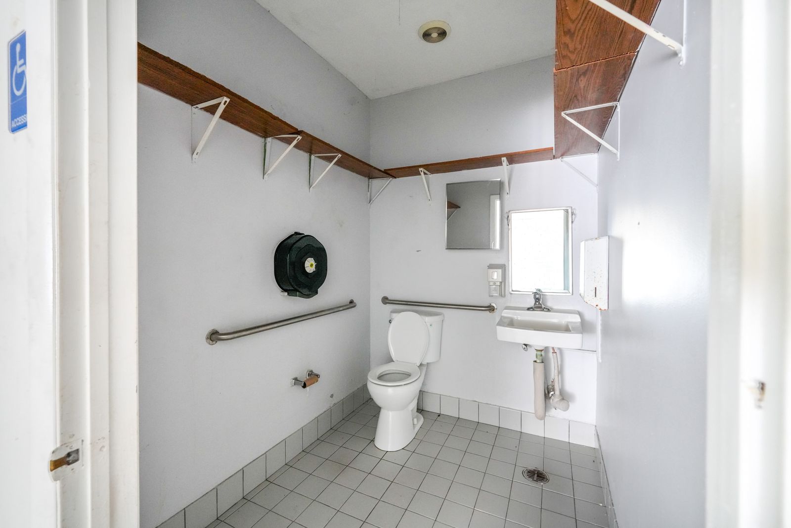 Restroom with a toilet, grab bar, sink and coat hooks.