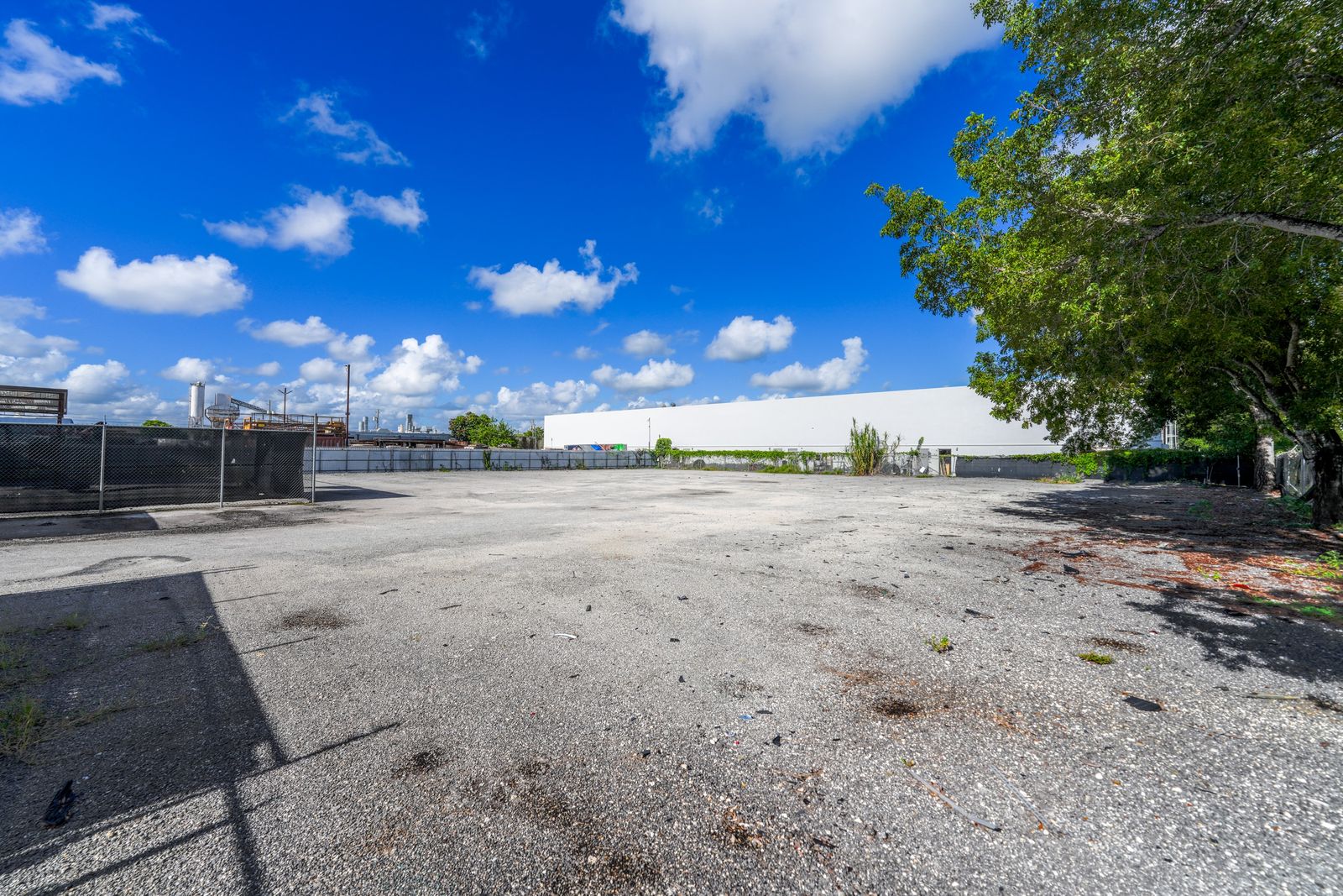 Open paved yard with a chain link fence on one side and a warehouse roofline visible in the distance.